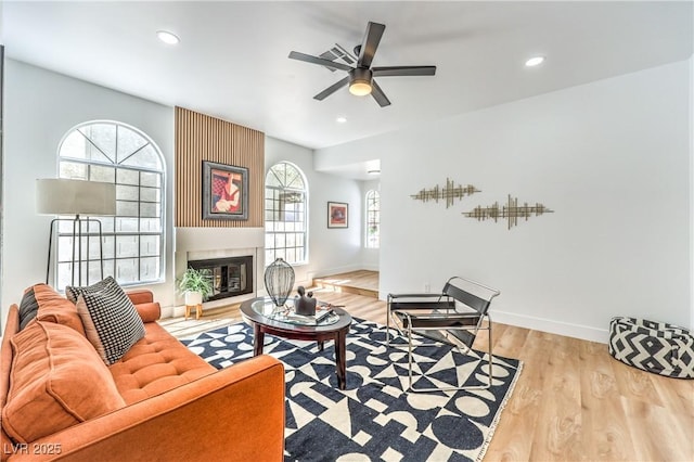 living area featuring wood finished floors, a ceiling fan, a large fireplace, baseboards, and recessed lighting