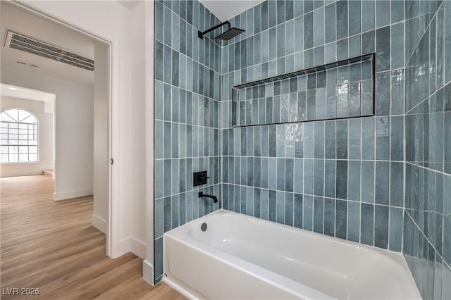 bathroom with baseboards, wood finished floors, and bathing tub / shower combination