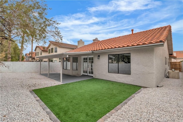 back of house with stucco siding, a patio area, a tiled roof, and a chimney