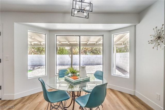 dining space with light wood finished floors, baseboards, and a chandelier