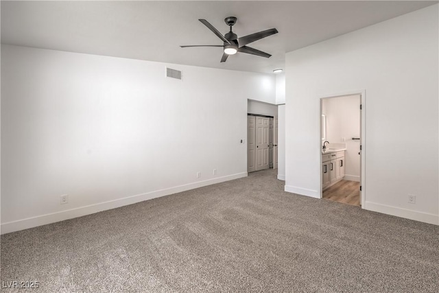 unfurnished bedroom with light colored carpet, baseboards, ensuite bathroom, and a sink