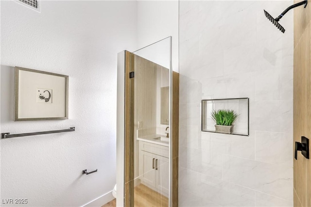 full bathroom featuring tiled shower, vanity, toilet, and baseboards