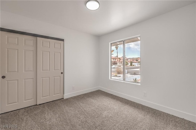 unfurnished bedroom featuring carpet floors, baseboards, and a closet