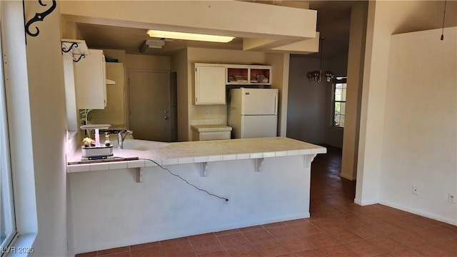 4285 El Como Way, Las Vegas, NV 89121 - kitchen with freestanding refrigerator, tile countertops, a peninsula, dark tile patterned floors, and open shelves