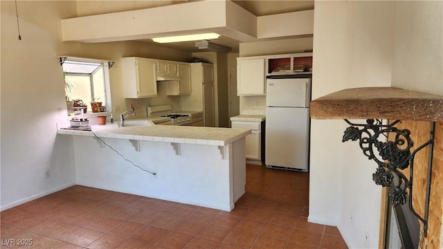 4285 El Como Way, Las Vegas, NV 89121 - kitchen featuring white appliances, tile counters, a peninsula, tile patterned floors, and a breakfast bar