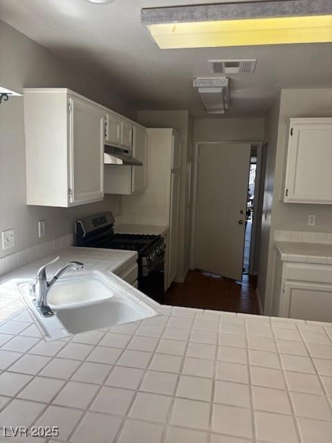 4285 El Como Way, Las Vegas, NV 89121 - kitchen featuring tile countertops, gas range oven, under cabinet range hood, and white cabinetry