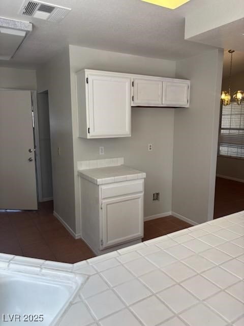 4285 El Como Way, Las Vegas, NV 89121 - kitchen with tile counters, white cabinetry, and a chandelier