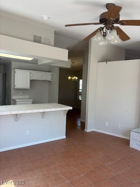 4285 El Como Way, Las Vegas, NV 89121 - kitchen featuring tile countertops, ceiling fan, a breakfast bar area, a chandelier, and white cabinetry