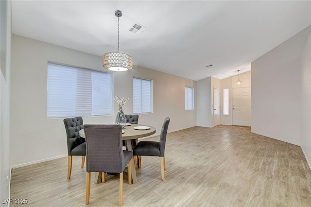 dining room with lofted ceiling, light wood-style flooring, and baseboards