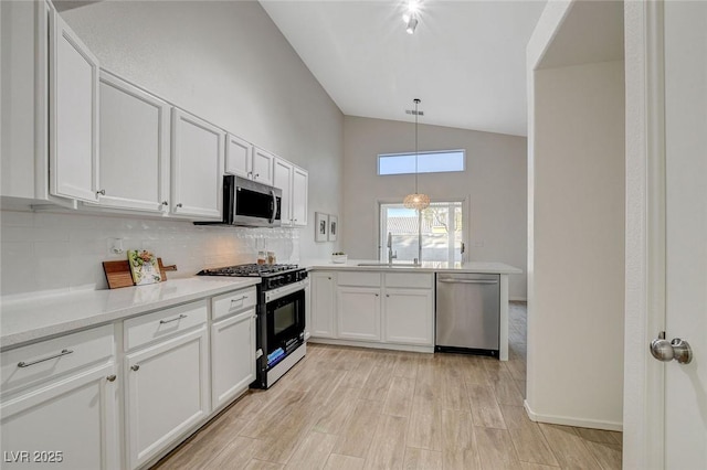 kitchen with appliances with stainless steel finishes, a sink, tasteful backsplash, white cabinetry, and light countertops