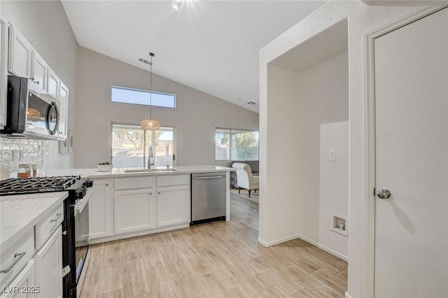 kitchen with stainless steel appliances, a sink, light countertops, a peninsula, and white cabinets