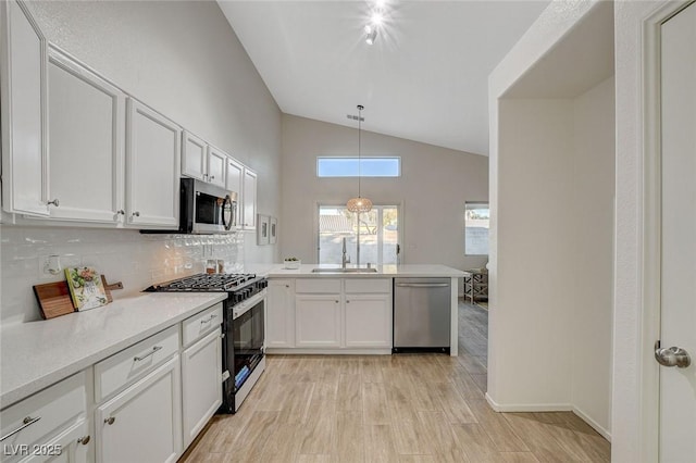 kitchen featuring appliances with stainless steel finishes, a sink, light countertops, backsplash, and a peninsula