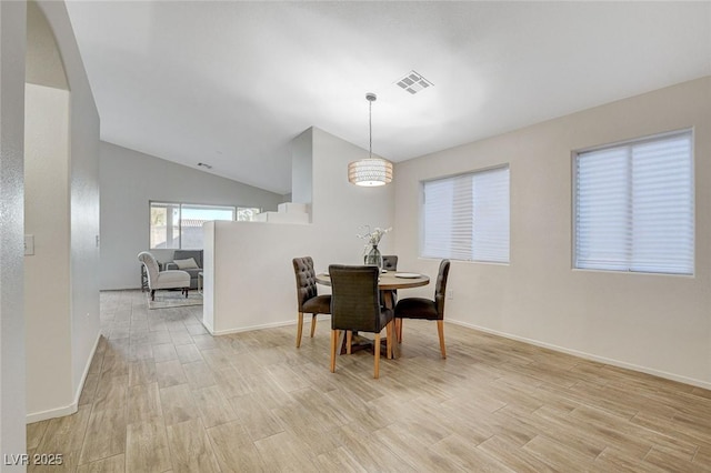 dining area featuring light wood-type flooring, baseboards, lofted ceiling, and arched walkways