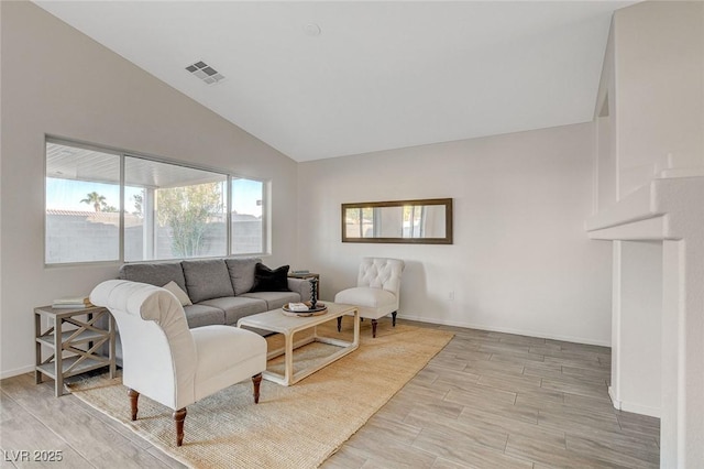 living room featuring lofted ceiling, light wood-style flooring, and baseboards