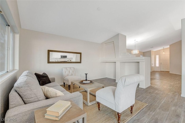 living room with lofted ceiling, light wood-type flooring, and baseboards