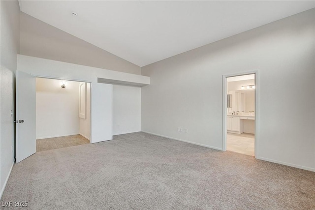 unfurnished bedroom featuring carpet flooring, lofted ceiling, a closet, ensuite bath, and baseboards