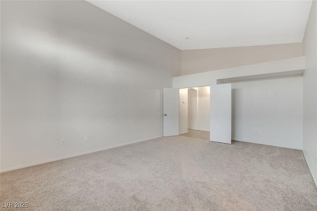 unfurnished bedroom with light carpet, high vaulted ceiling, and a closet