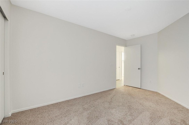 spare room with light carpet and baseboards