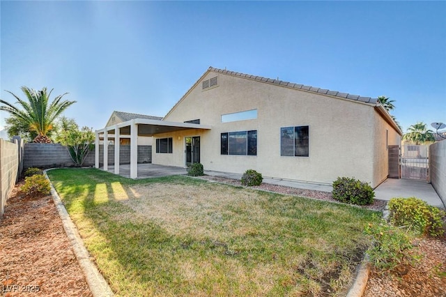 rear view of property with a patio area, stucco siding, and a gate