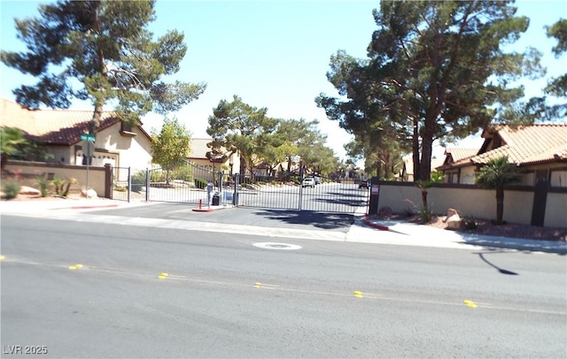 3954 Saddlewood Ct, Las Vegas, NV 89121 - view of asphalt street with a gate, sidewalks, and curbs