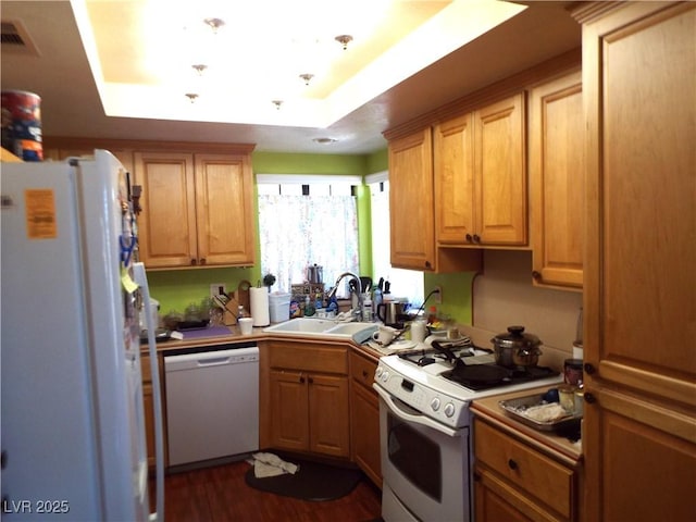 3954 Saddlewood Ct, Las Vegas, NV 89121 - kitchen with white appliances, a sink, a tray ceiling, dark wood-type flooring, and light countertops