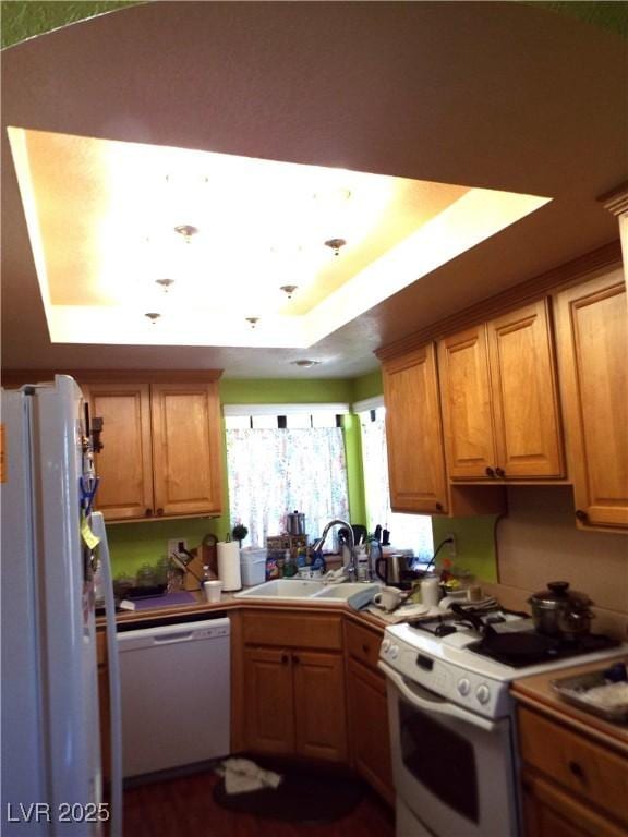 3954 Saddlewood Ct, Las Vegas, NV 89121 - kitchen featuring white appliances, a sink, a tray ceiling, and brown cabinets