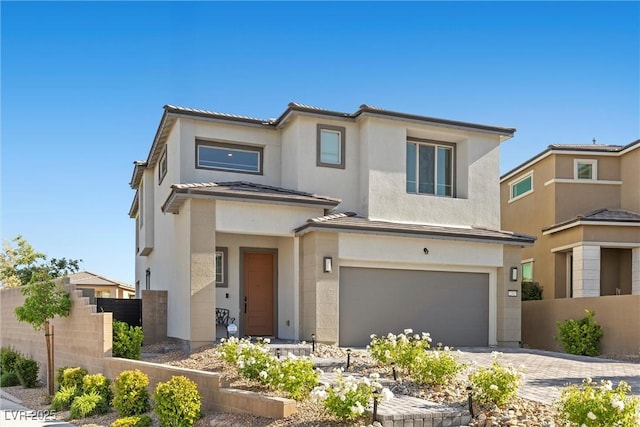 view of front facade with fence, an attached garage, stucco siding, and driveway
