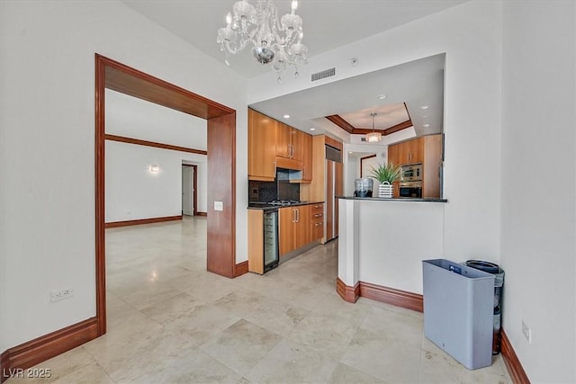 kitchen featuring brown cabinets, baseboards, dark countertops, built in appliances, and a tray ceiling