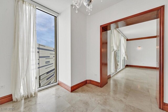 empty room with baseboards and a chandelier