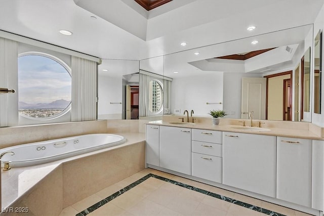 full bathroom featuring a raised ceiling, a garden tub, double vanity, recessed lighting, and ornamental molding