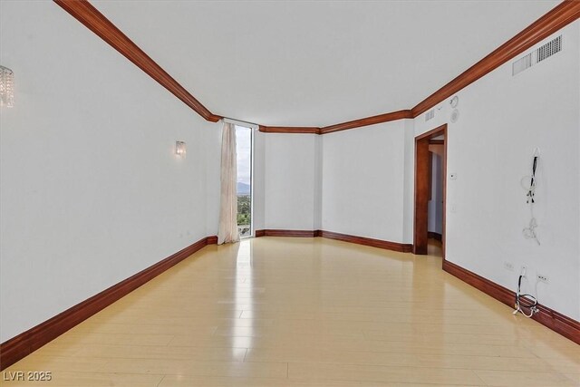empty room featuring ornamental molding and baseboards