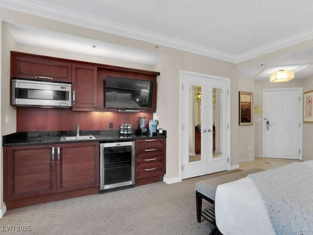 indoor wet bar featuring beverage cooler, stainless steel microwave, french doors, crown molding, and baseboards