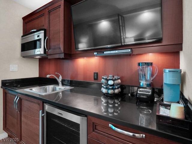 kitchen featuring stainless steel microwave, wine cooler, dark countertops, and a sink
