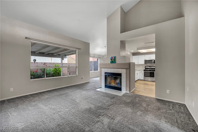 2124 Rising Mist St, Las Vegas, NV 89134 - unfurnished living room with light carpet, a tiled fireplace, baseboards, and a towering ceiling