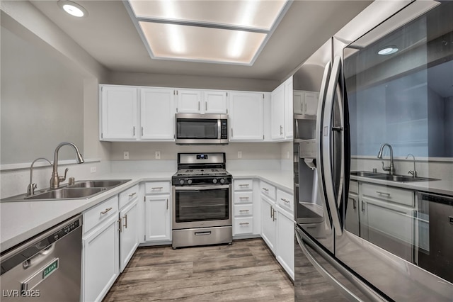 2124 Rising Mist St, Las Vegas, NV 89134 - kitchen with appliances with stainless steel finishes, a sink, white cabinetry, light wood-style flooring, and recessed lighting