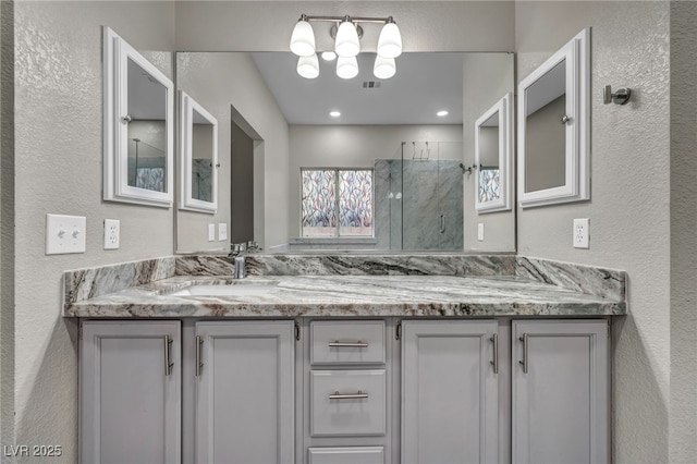 2124 Rising Mist St, Las Vegas, NV 89134 - bathroom featuring a marble finish shower, double vanity, a textured wall, and a chandelier