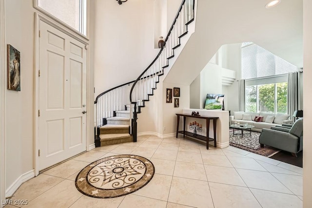 foyer with a high ceiling, light tile patterned flooring, stairs, and baseboards