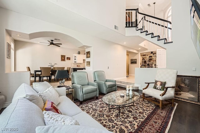 living room with a ceiling fan, wood finished floors, stairway, and a high ceiling