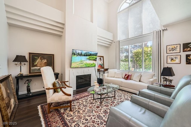 living room featuring dark wood finished floors, a high end fireplace, and a high ceiling