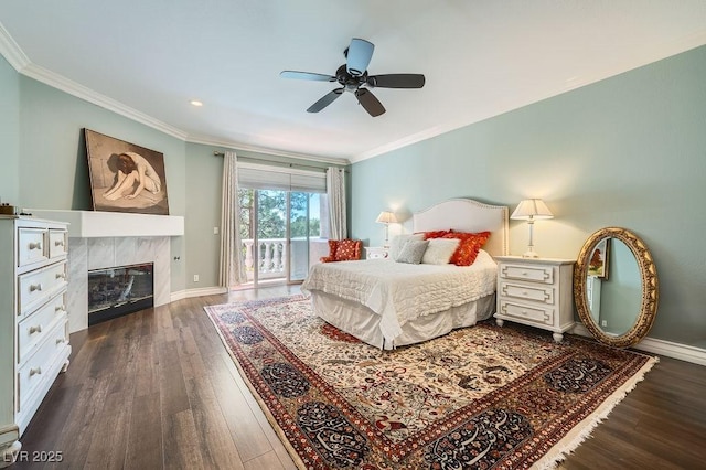 bedroom featuring access to exterior, dark wood finished floors, ornamental molding, a tile fireplace, and baseboards