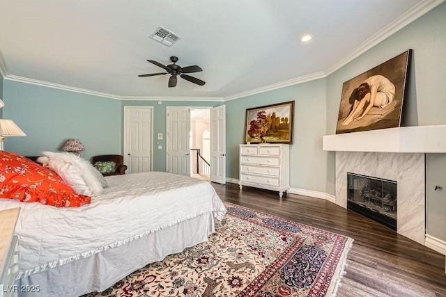 bedroom featuring ornamental molding, wood finished floors, a high end fireplace, baseboards, and a ceiling fan