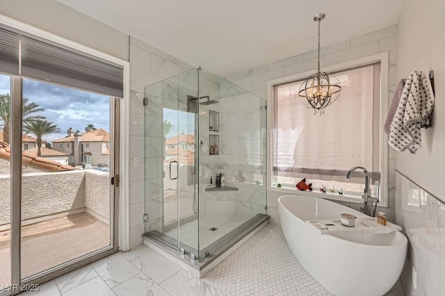 bathroom featuring a freestanding bath, a stall shower, a chandelier, and marble look tiles