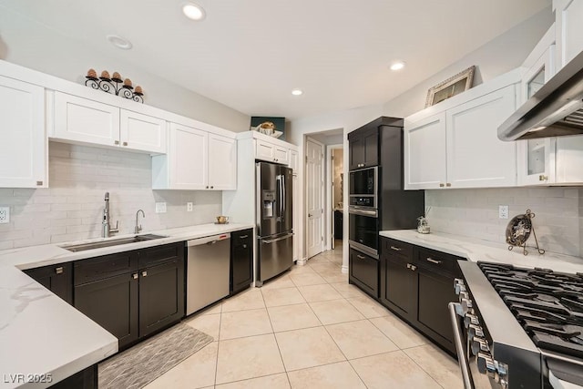 kitchen with stainless steel appliances, a sink, white cabinetry, wall chimney range hood, and recessed lighting