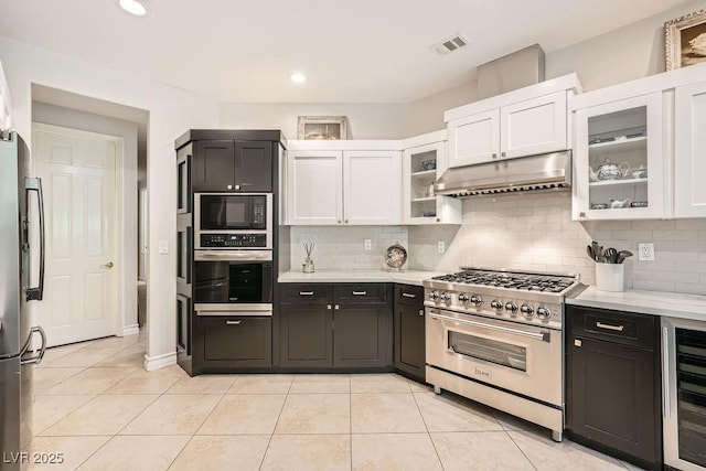 kitchen with appliances with stainless steel finishes, wine cooler, white cabinetry, under cabinet range hood, and recessed lighting