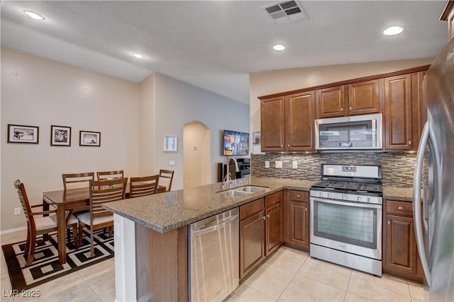 3712 Rocklin Peak Ave, North Las Vegas, NV 89081 - kitchen with appliances with stainless steel finishes, a sink, arched walkways, a peninsula, and backsplash