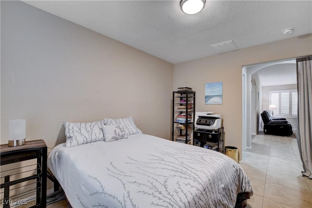 3712 Rocklin Peak Ave, North Las Vegas, NV 89081 - bedroom featuring arched walkways, light tile patterned floors, a textured ceiling, and baseboards