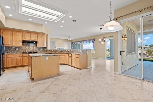 2868 Foxtail Creek Ave, Henderson, NV 89052 - kitchen with under cabinet range hood, a kitchen island, tasteful backsplash, light stone counters, and gas cooktop