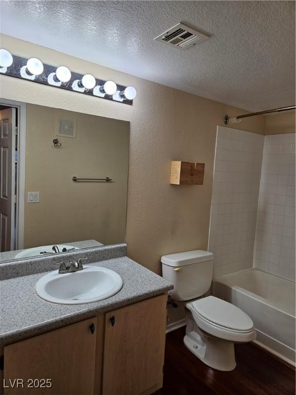555 E Silverado Ranch Blvd Unit 2052, Las Vegas, NV 89183 - bathroom with wood finished floors, toilet, vanity, a textured ceiling, and  shower combination