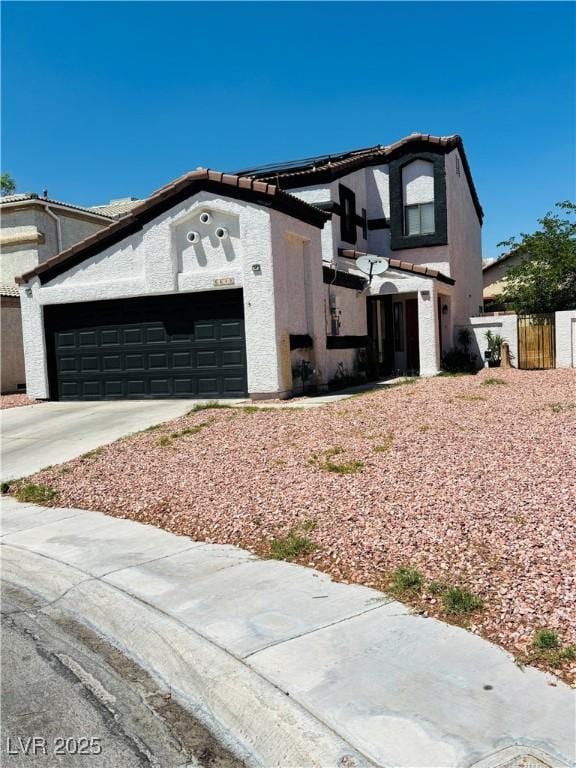 view of front of house with an attached garage, concrete driveway, stucco siding, and fence
