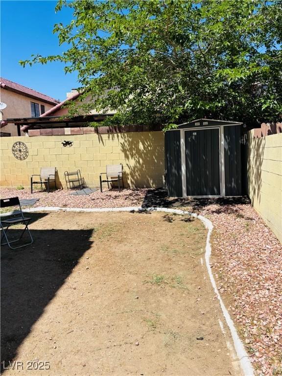 fenced backyard featuring a storage shed and an outbuilding